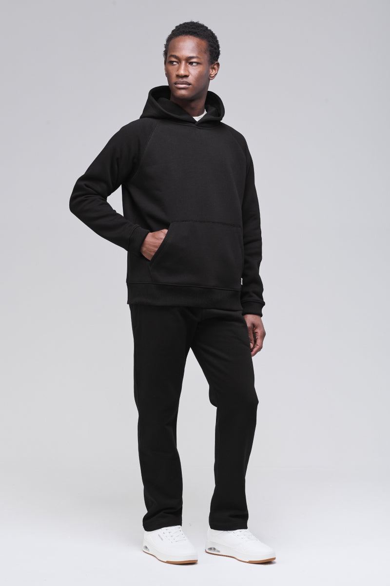 Male model wearing black classic hoodie, hand in pocket